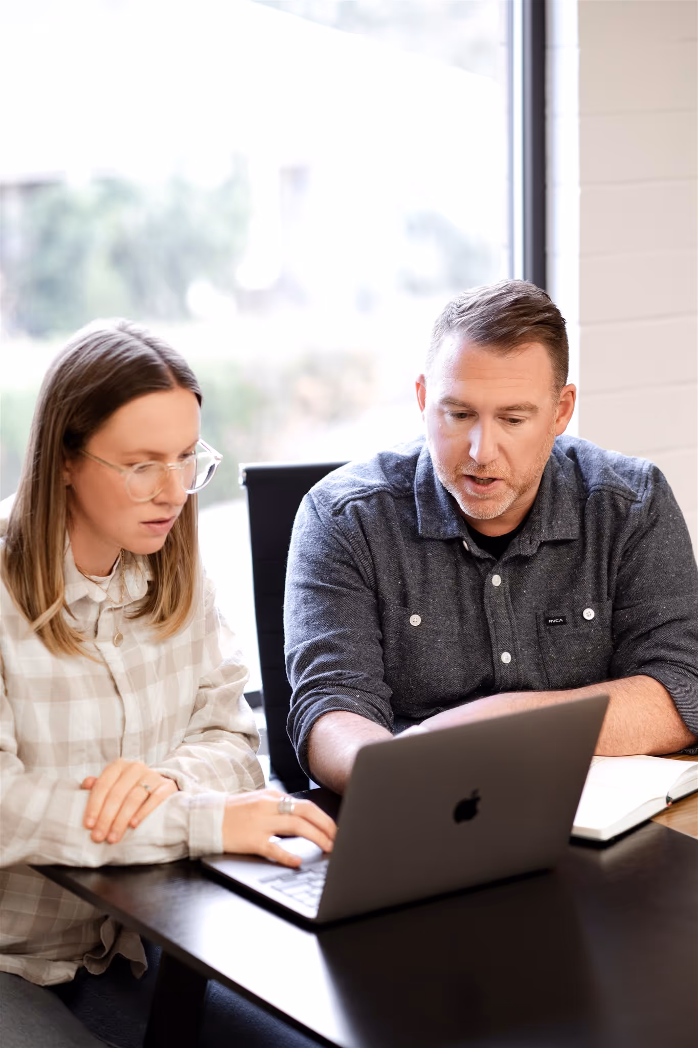 Two teammates reviewing work on a laptop